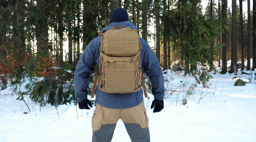 Muž v zimných nohaviciach s batohom v zasneženom lese