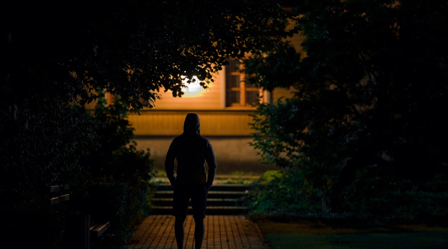 Muž stojí pred domom s rozsvietenými svetlami