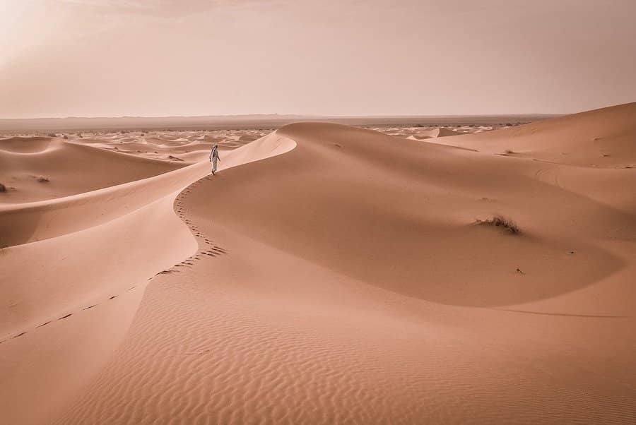 Muž chodiaci po dunách v púšti