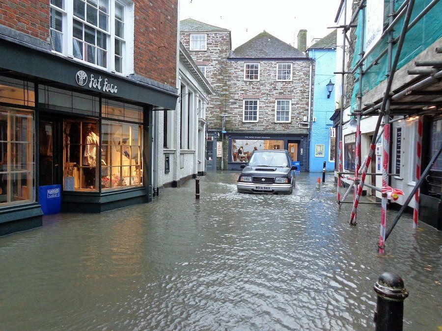 Zaplavená ulice s obchodmi a autom