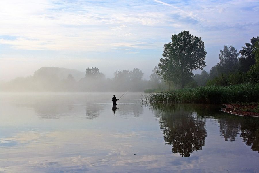 Rybár loviaci z vody skoro ráno pred svitaním