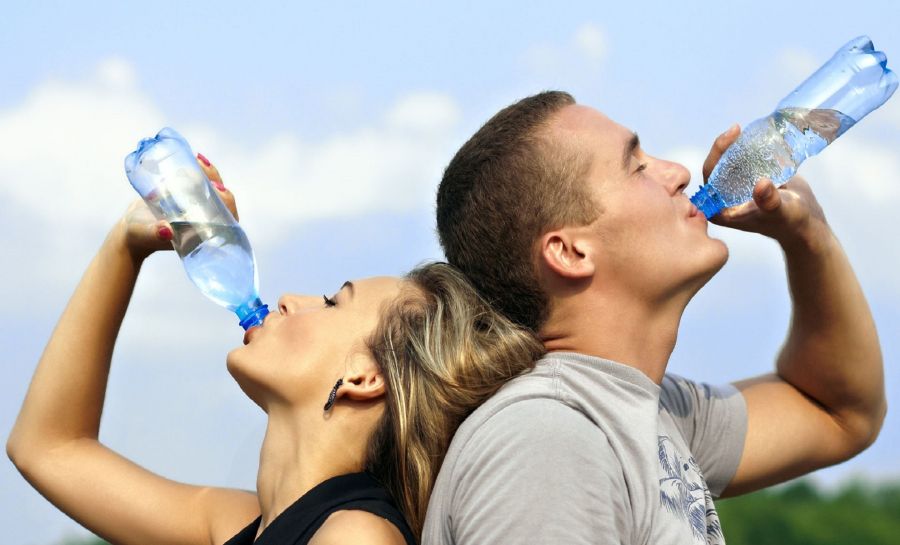 Muž a žena pijú vodu z fľaše